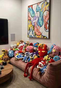 a large group of stuffed animals sitting on top of a couch in front of a flat screen tv