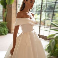 a woman in a white wedding dress is posing for the camera with her hand on her hip