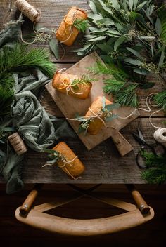 some food is laying out on a cutting board and surrounded by greenery, sprigs and twine