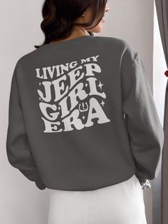 Jeep Girl For the adventurous, the bold, and the women who are not afraid to hit the off-road trails, our "Living My Jeep Girl Era White Print Sweatshirt" is the perfect companion. Embodying both comfort and quality, this off-road women's apparel is a testament to the rugged spirit of the Jeep Girl. Designed with a classic crewneck style, this sweatshirt is as versatile as you are. Whether you're conquering the wilderness behind the wheel, or simply unwinding at a campfire under the stars, it's a garment that works as hard as you do. Join the She Jeep Club The She Jeep Club isn't just a group, it's a community of women who share a passion for off-road driving and adventure. When you wear this sweatshirt, you're not just making a fashion statement, you're joining a sisterhood of like-minded Trendy Outdoor Sweatshirt With Graphic Print, Trendy Outdoor Graphic Print Sweatshirt, Trendy Graphic Print Sweatshirt For Outdoor, Long Sleeve Letter Print Adventure T-shirt, Long Sleeve Letter Print T-shirt For Adventure, Gray Graphic Print Top For Outdoor Activities, Gray Tops For Outdoor Activities In Fall, Trendy Graphic Print Tops For Outdoor Activities, Gray Tops For Fall Outdoor Activities