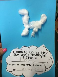 a hand holding up a piece of paper with clouds on it