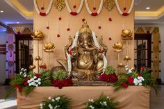 a golden buddha statue sitting on top of a table next to red and white flowers