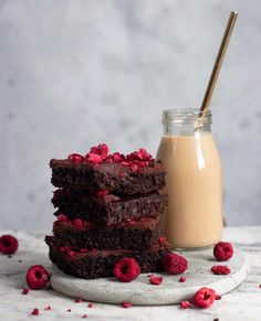 three chocolate brownies stacked on top of each other with raspberries around them