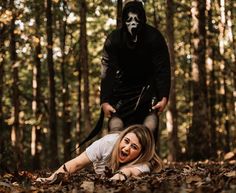 a woman laying on the ground in front of a man wearing a mask and holding a knife