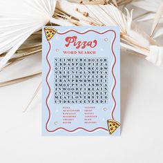 a pizza word search card sitting next to some palm leaves