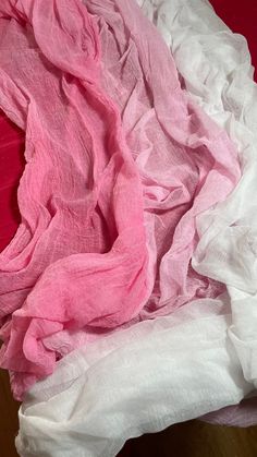 a pile of pink and white fabric on top of a wooden table