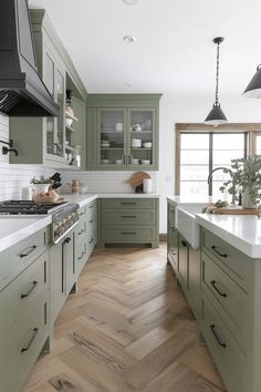 a large kitchen with green cabinets and white counter tops, wood flooring and wooden floors