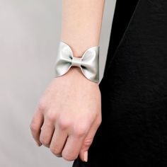 "Silver Bow Tie Vegan Leather Wide Cuff Bracelet by ForgottenCotton Get Festive. Our silver bow tie cuff is perfect 'oh so adorable' accessory. Dressed up or down, it is versatile, cute, and sure to get tons of compliments. In always stylish metallic silver, it will add a pop to any outfit. Why we love it: Our cuffs are made to be versatile. You can wear our cuffs on either your wrist or your scarf (or both!) We chose high quality vegan leather that has the look and feel of leather without the g Modern Adjustable Cuff Bracelet For Party, Modern Adjustable Cuff Bracelet For Parties, Adjustable Modern Cuff Bracelet For Party, Adjustable Wrist Strap Wristlet For Party, Adjustable Wristlet With Wrist Strap For Party, Elegant Leather Cuff Bracelet For Party, Leather Cuff Bracelet For Party, Formal Adjustable Bracelet With Wrist Strap, Formal Adjustable Bracelets With Wrist Strap