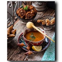 a bowl of soup on a wooden table with other bowls and plates full of food