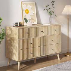 a wooden dresser sitting next to a lamp on top of a hard wood floor in front of a white wall