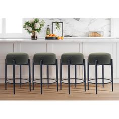 four stools in front of a counter with flowers on it