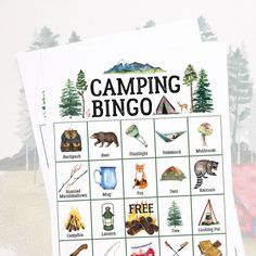 the camping bingo game is on top of a pile of papers with trees in the background