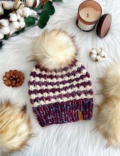 a purple and white knitted hat sitting on top of a fur rug