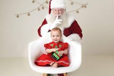 a baby sitting in a chair with santa clause on it