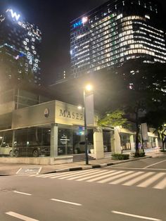 an empty street at night with tall buildings in the background