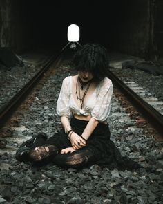 a woman is sitting on the train tracks