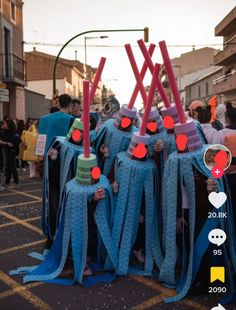 several people dressed up in blue and red costumes, standing on the street with their heads covered by sticks