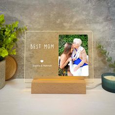 a personalized wooden photo frame with the words best mom on it next to a potted plant