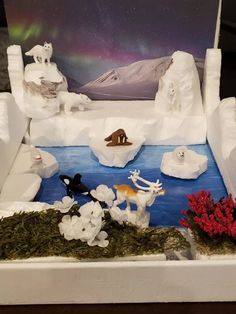 a display case with fake snow sculptures and flowers on the bottom, in front of an aurora scene