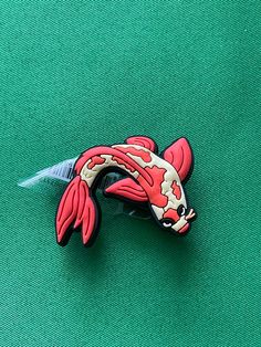 a red and white fish pin sitting on top of a green surface