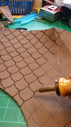 a person using a wood carving tool to cut out the top of a piece of fabric