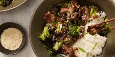 a bowl filled with rice, broccoli and beef on top of a table