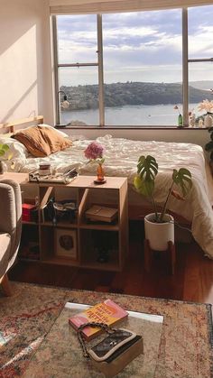 a bedroom with a large window and a bed in front of the window is filled with books