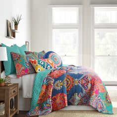 a bed with colorful comforters and pillows on it