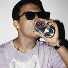 a man wearing sunglasses drinking from a can