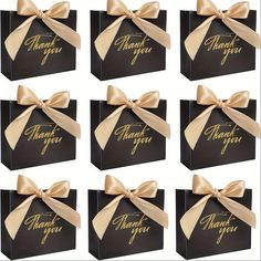 six black boxes with gold bows and thank you written on the side, all wrapped in satin ribbon