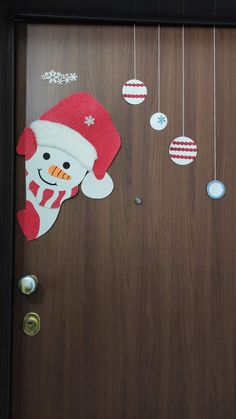 a wooden door decorated with christmas decorations and ornaments hanging from the front, along with a snowman ornament