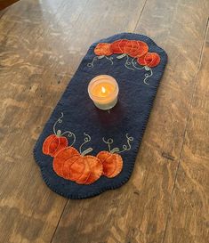 a table with a candle on top of it and a place mat that has oranges on it