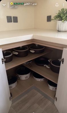 an open cabinet with pots and pans in it