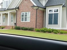 a car is parked in front of a brick house with white windows and shutters