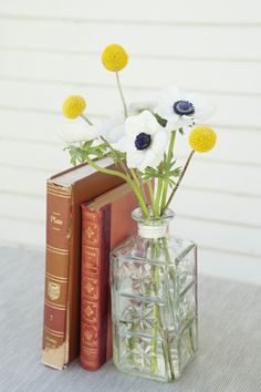 a vase filled with white and yellow flowers next to two books