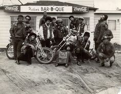 an old black and white photo of men on motorcycles in front of a bar - b - que