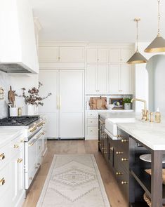 a kitchen with white cabinets and gold accents on the countertops, along with an area rug