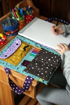 a person sitting at a desk with a notebook and pencils in front of them