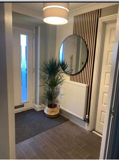 an entry way with a potted plant and round mirror