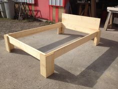 a wooden bed frame sitting in front of a red building