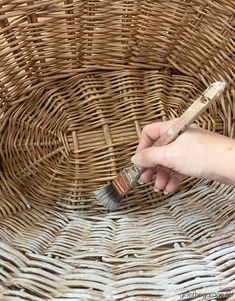 a person holding a paintbrush in their left hand and painting the wicker basket