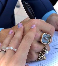 two people holding each other's hands while writing on a piece of paper with a pen