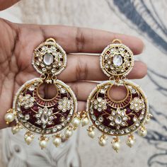 Elevate your bridal ensemble with these stunning Ruby and Pearl Chandbali Earrings. Designed as large chandbalis, they feature ruby stones complemented by pearl drops, creating a perfect blend of traditional elegance and modern sophistication. Ideal for bridal wear or special occasions, these earrings make a bold and luxurious statement. Length: 3" to 3.5" Material: 24Kt gold foil, lac Stones: Kundans, semi precious rubies, semi precious pearls, semi precious turquoise Festive Hand Set Pearl Chandbali Earrings, Festive Hand Set Chandbali Pearl Earrings, Festive Hand-set Pearl Chandbali Earrings, Festive Handcrafted Chandbali Pearl Earrings, Festive Ruby Chandbalis For Diwali, Heavy White Chandbalis For Reception, Fusion Style Wedding Chandbalis, Fusion Chandbali Pearl Drop Bridal Earrings, Fusion Chandbali Bridal Earrings With Pearl Drop