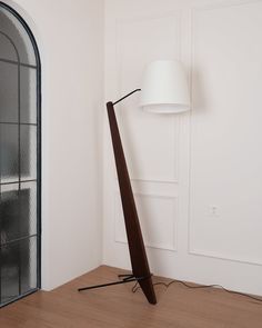 a floor lamp sitting on top of a hard wood floor next to a white wall