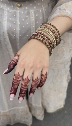 a woman's hands with hennap and bracelets on her wrist,