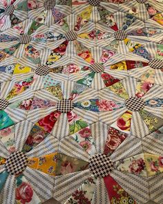 an old quilt is laying on top of a tablecloth covered with flowers and checkered fabric