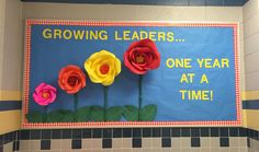 a bulletin board with paper flowers on it in a school bathroom area that says growing leaders one year at a time