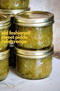 four jars filled with pickles sitting on top of a table