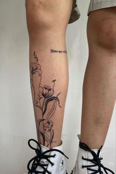 a woman's legs with flowers and words on the lower part of her leg