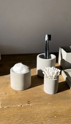 three toothbrushes in cups sitting on a wooden table